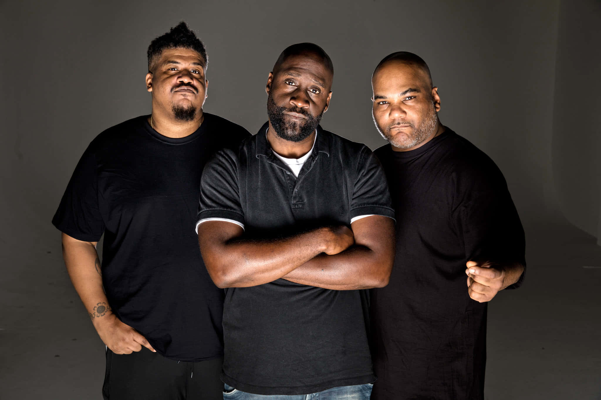 Three Men Standing In Front Of A Gray Background Wallpaper