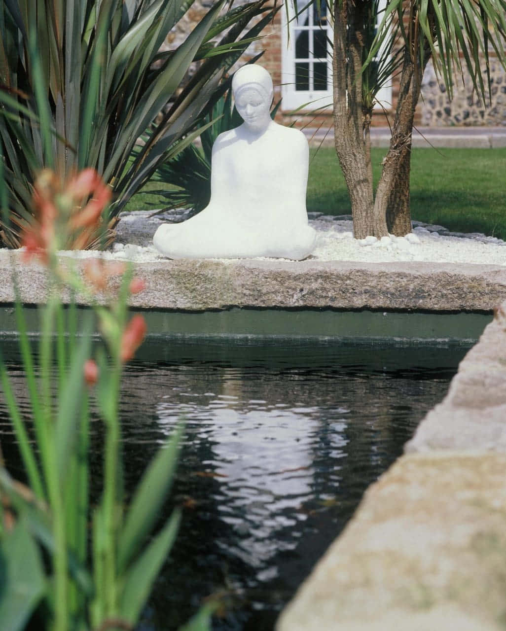 Tranquil Buddha Statueby Pond Wallpaper