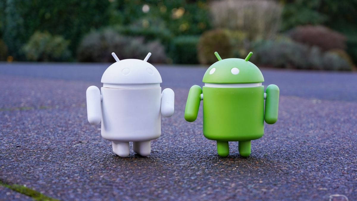 Two Android Toys Standing Next To Each Other Wallpaper