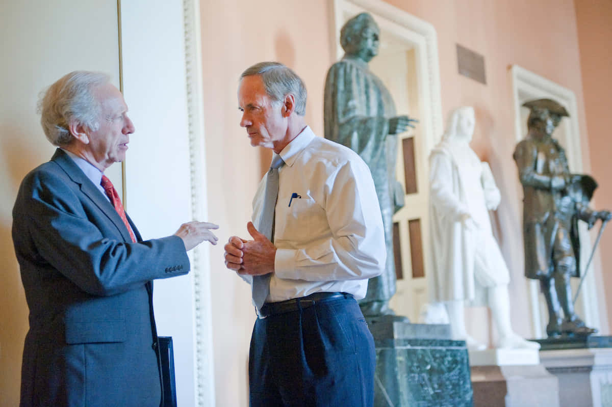 Two Men Conversing Near Statues Wallpaper