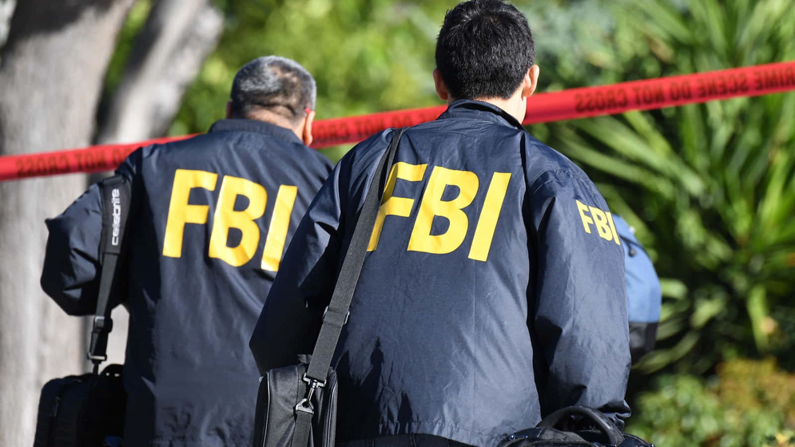 Two Men In Fbi Jackets Walking Down A Street Wallpaper