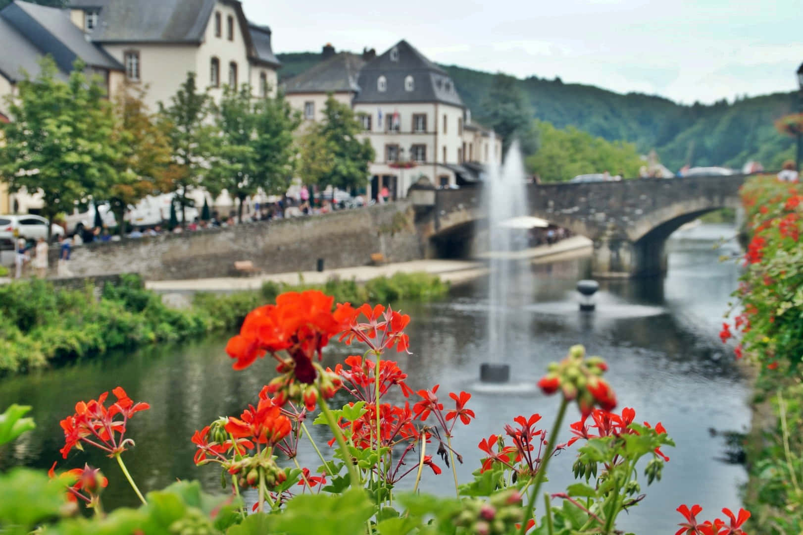 Vianden River Viewwith Flowersand Bridge Wallpaper