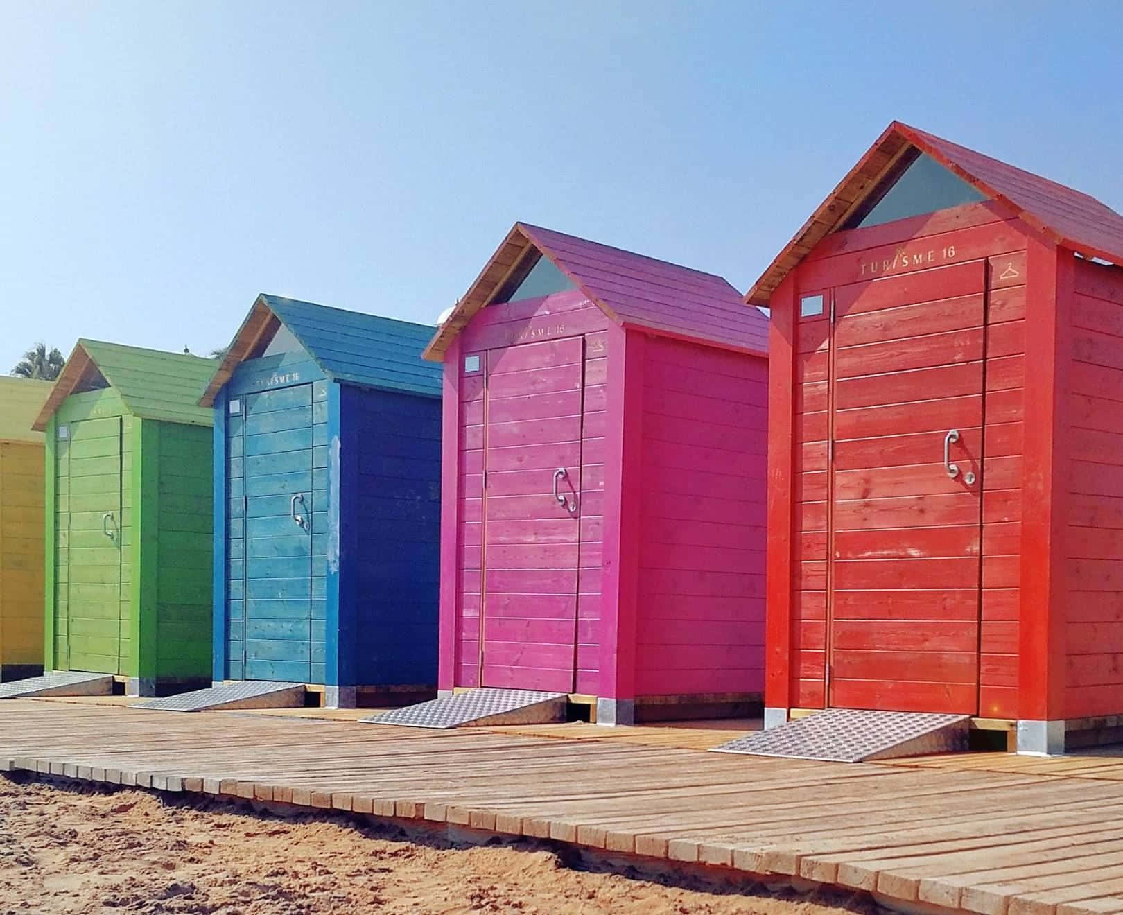 Vibrant Beach Huts Basking In The Sun Along The Shoreline Wallpaper