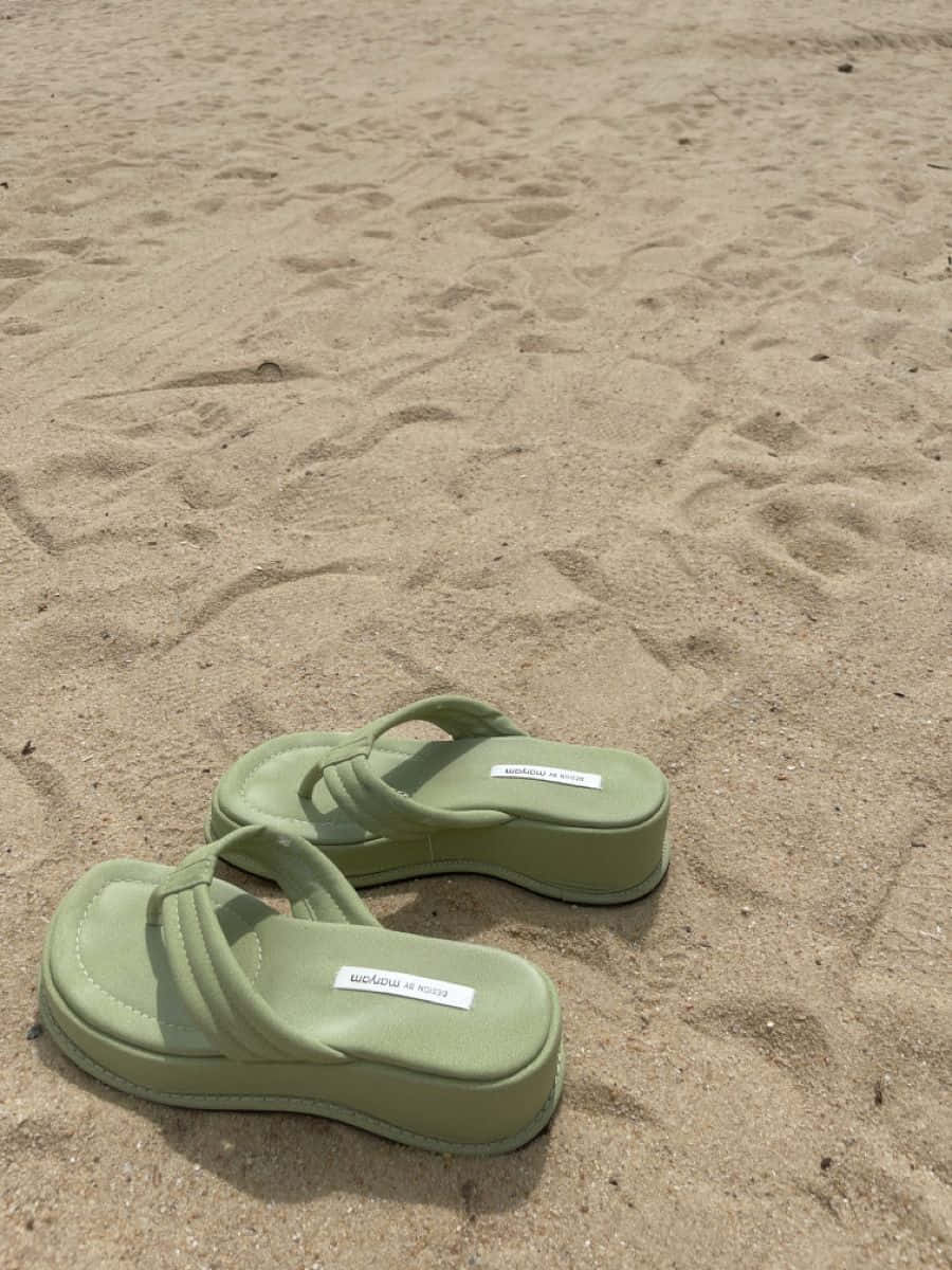 Vibrant Beach Sandals On Sunlit Sandy Shore Wallpaper