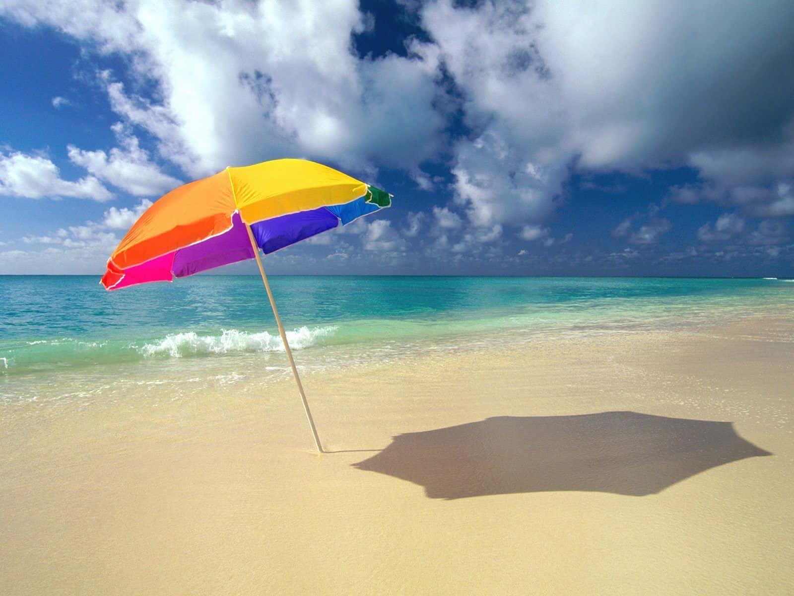 Vibrant Beach Umbrella Providing Shade On A Sunny Day Wallpaper