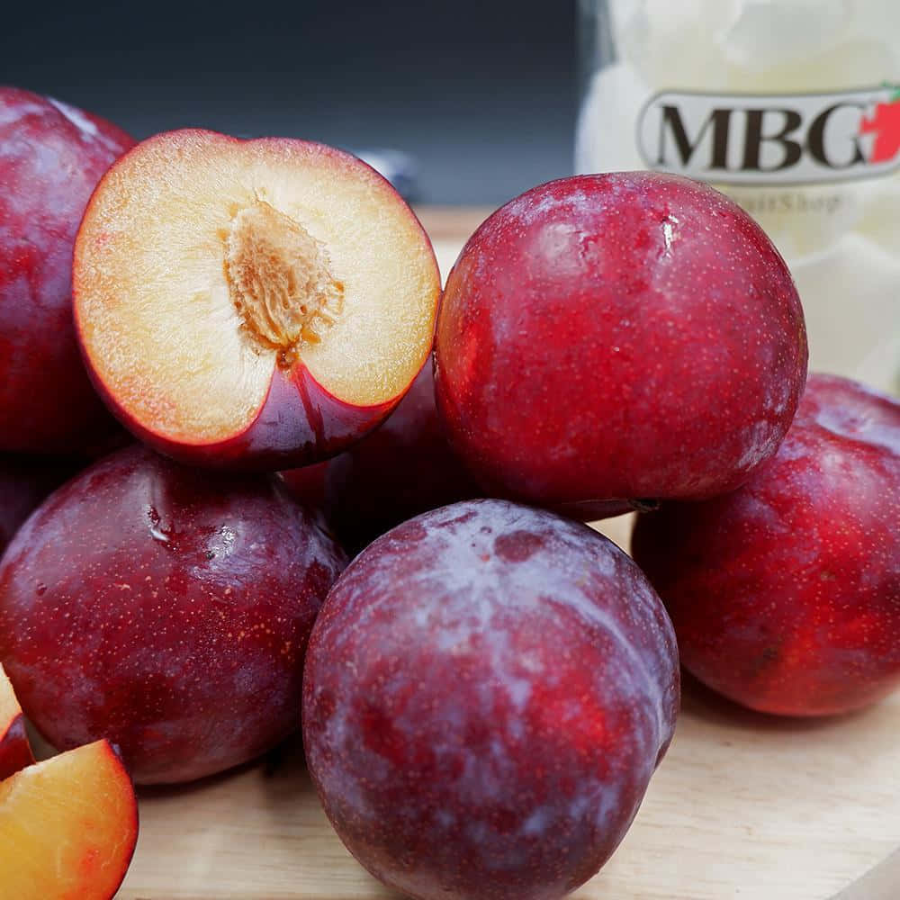 Vibrant Red Plums On A Tree Wallpaper