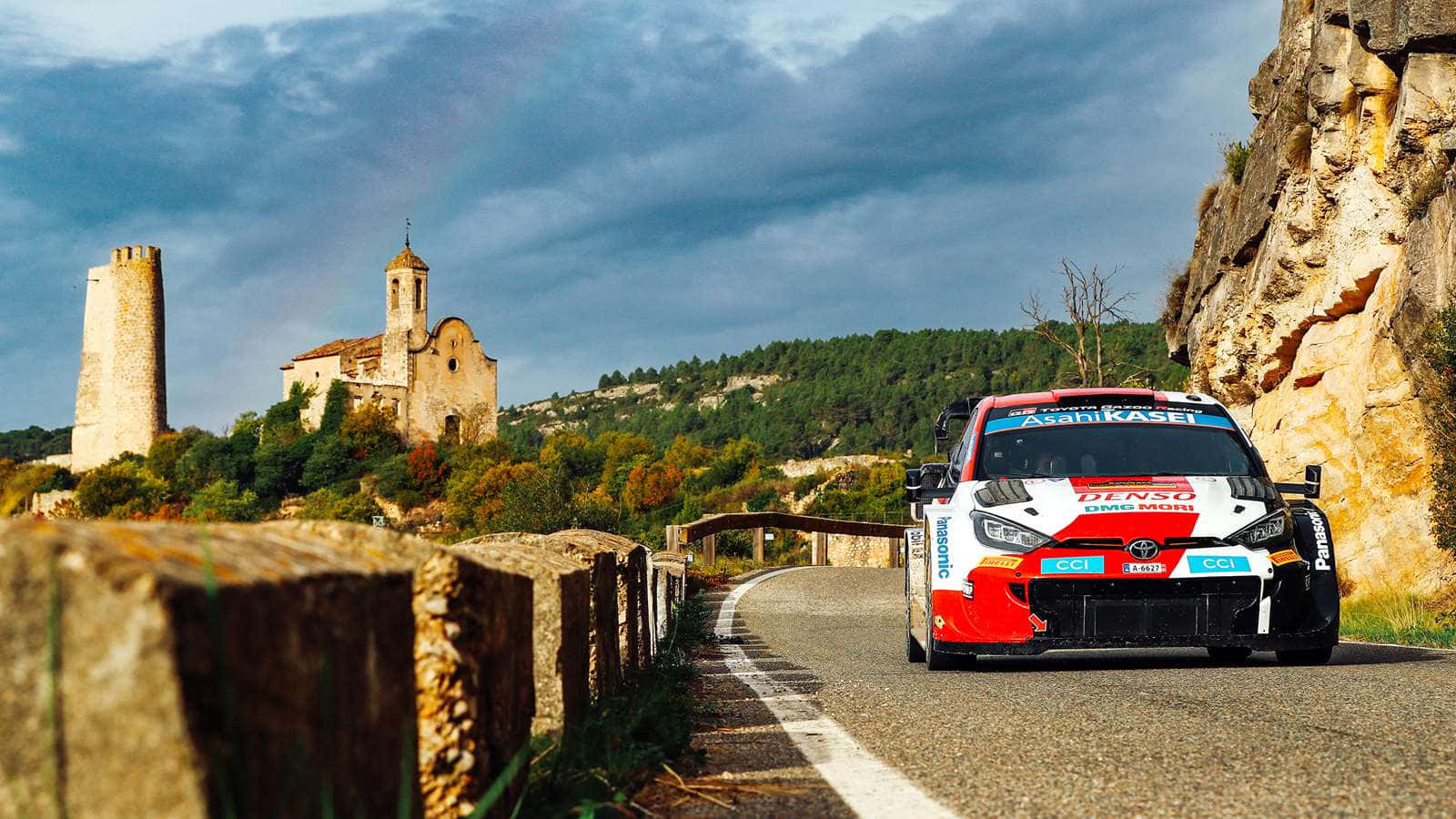 W R C Rally Car Speeding Past Historic Site Wallpaper