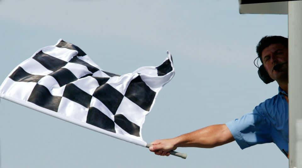 Waving Chequered Flag On Racing Track Wallpaper