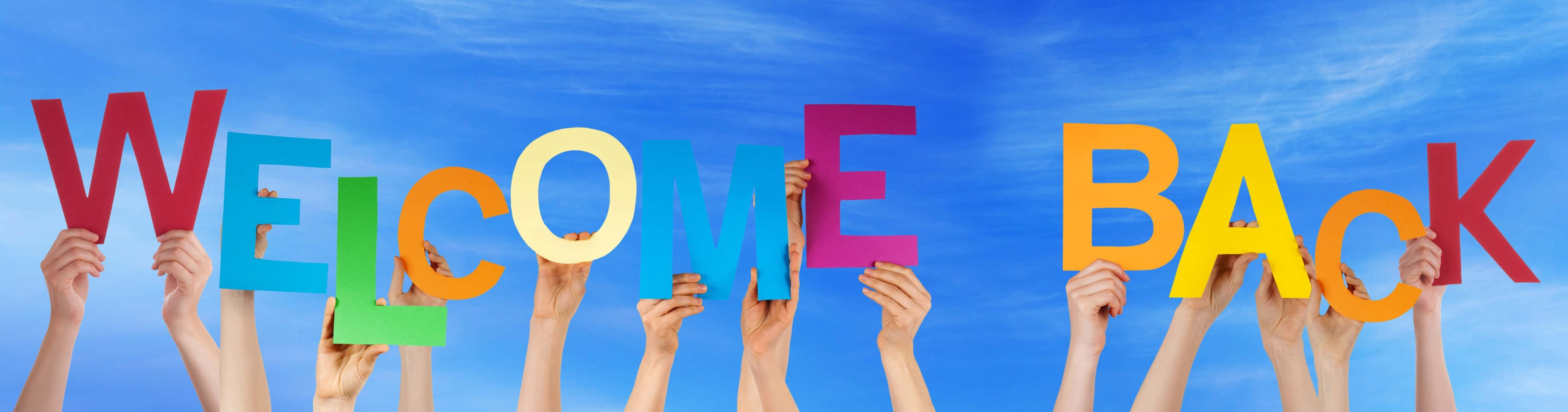 Welcome Back Sign Held Against Sky Wallpaper