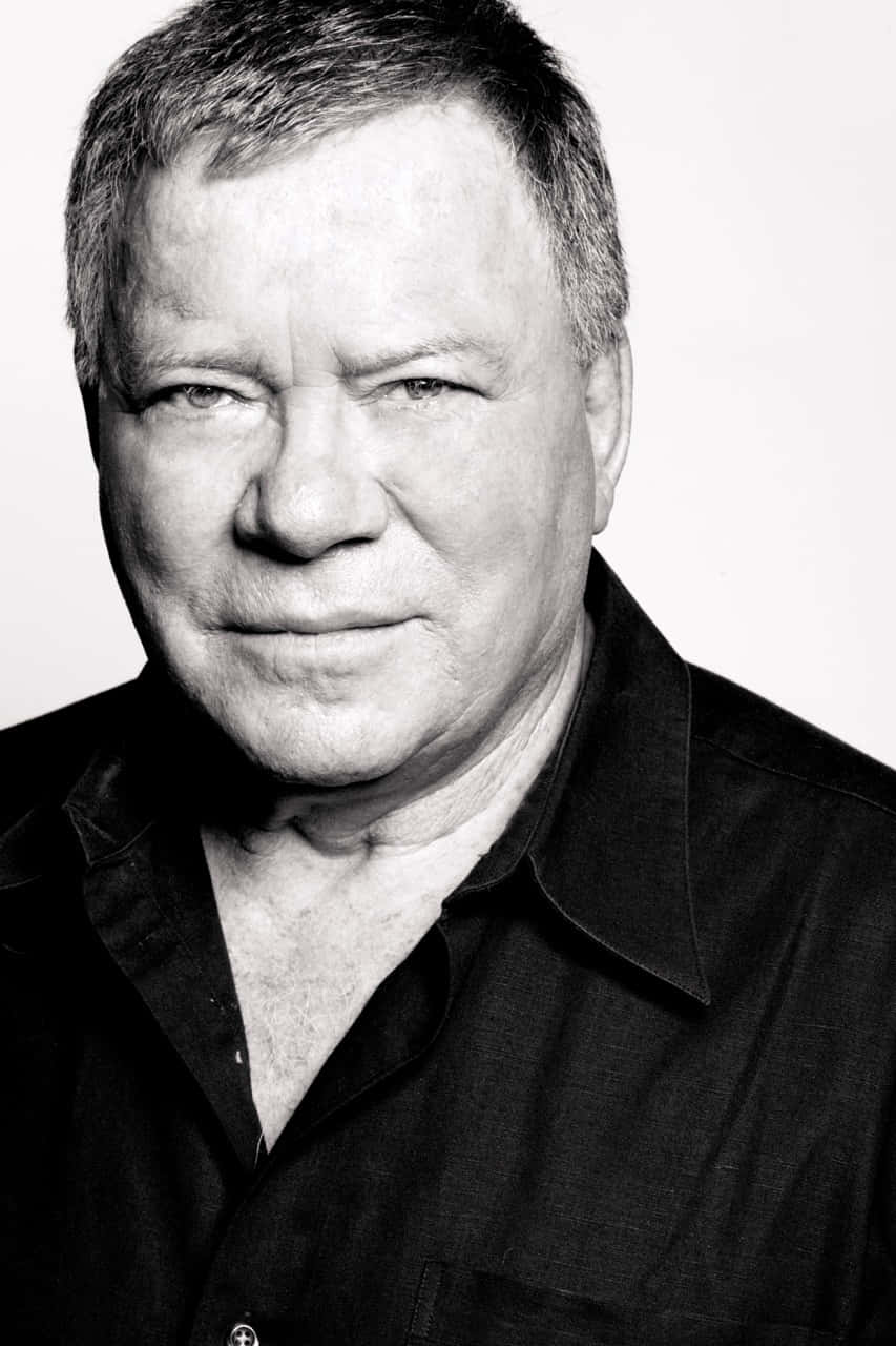 William Shatner Striking A Pose In A Black Suit And Tie Wallpaper