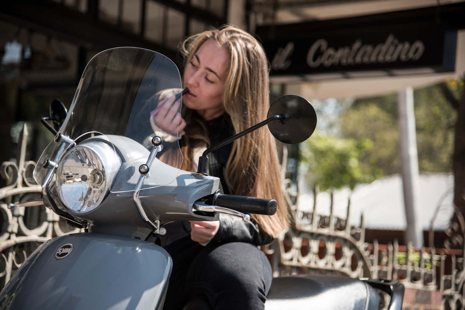 Woman Applying Makeupon Scooter Wallpaper