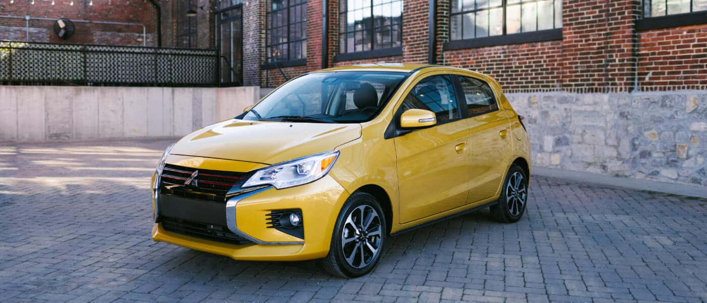 Yellow Mitsubishi Mirage Urban Setting Wallpaper