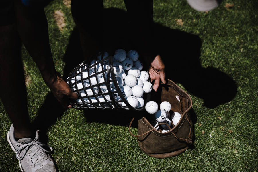 4k Person Pushing Golf Balls Towards Bag Wallpaper