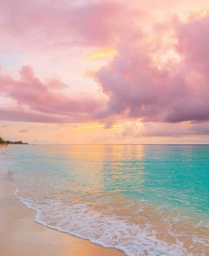 A Beach With A Pink Sunset And Water Wallpaper