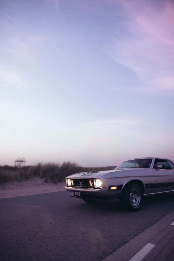 A Classic Car Driving Down The Road Wallpaper