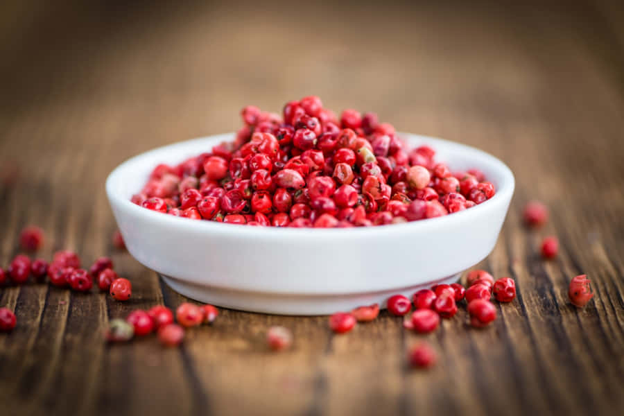 A Close-up Of Pink Peppercorns On A Wooden Surface Wallpaper