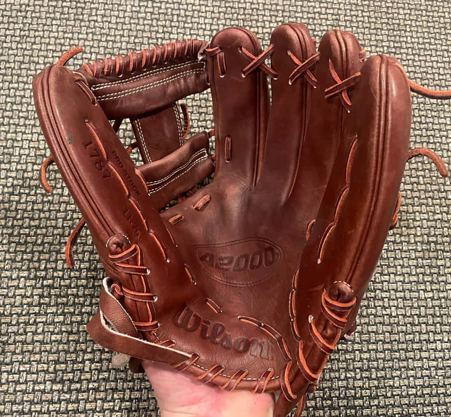 A Close-up View Of High-quality Baseball Gloves On A Wooden Surface Wallpaper