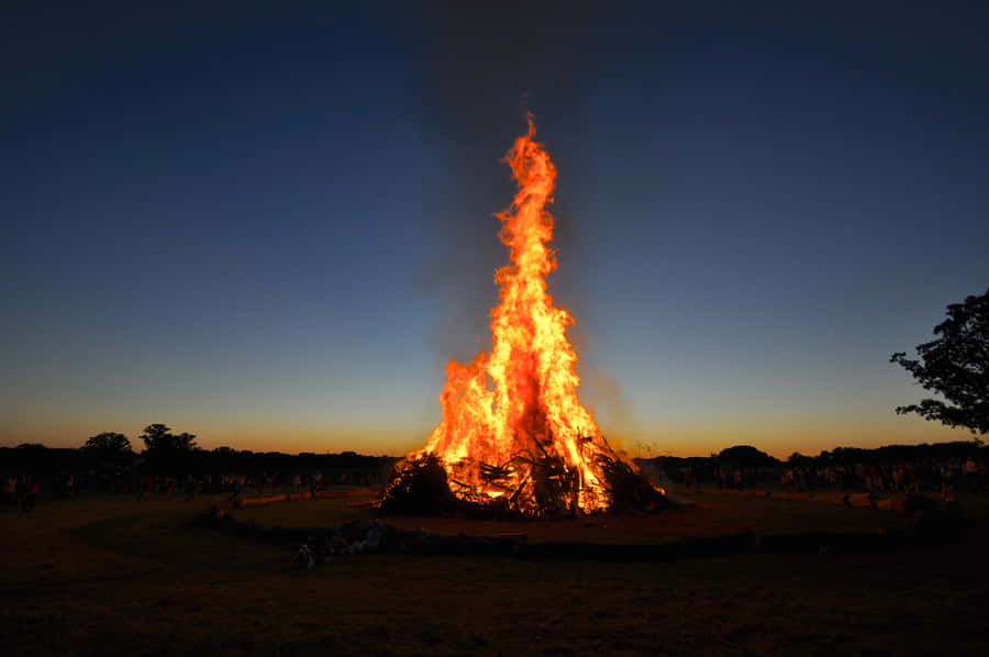 A Cozy Fall Bonfire In The Woods Surrounded By Beautiful Autumn Foliage Wallpaper