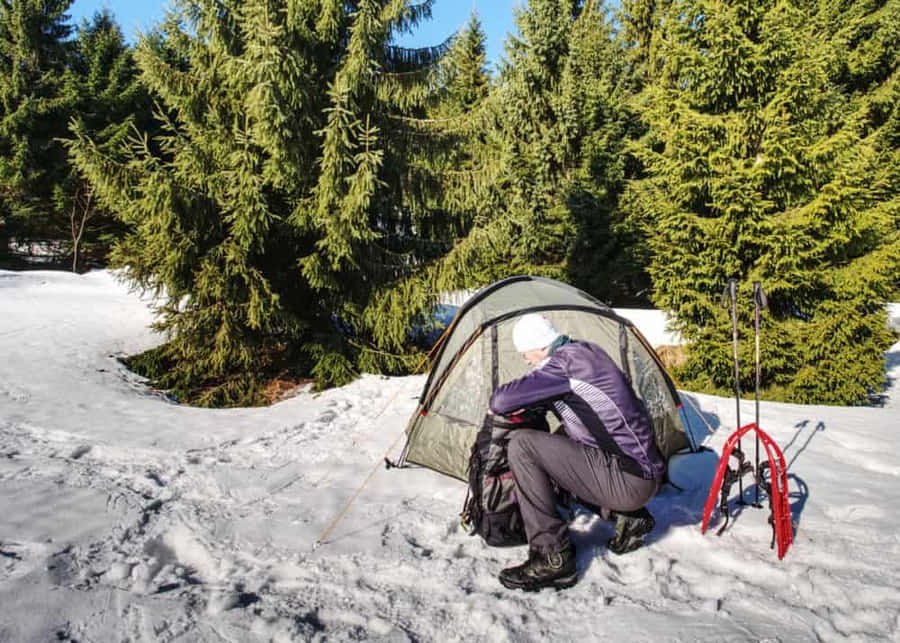 A Cozy Winter Camping Experience In A Snow-covered Forest Wallpaper