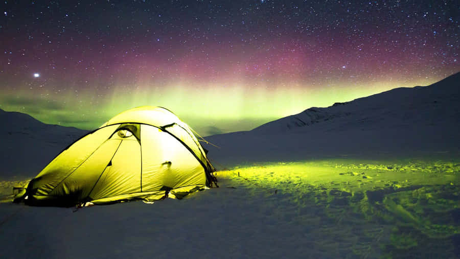 A Cozy Winter Camping Setup In A Snowy Forest Landscape Wallpaper