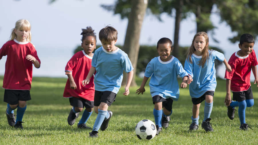 A Group Of Enthusiastic Kids Enjoying A Thrilling Soccer Game Wallpaper