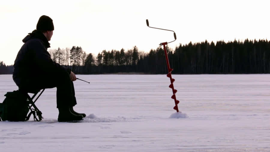 A Group Of Ice Anglers Enjoying A Day Of Ice Fishing On A Frozen Lake Wallpaper