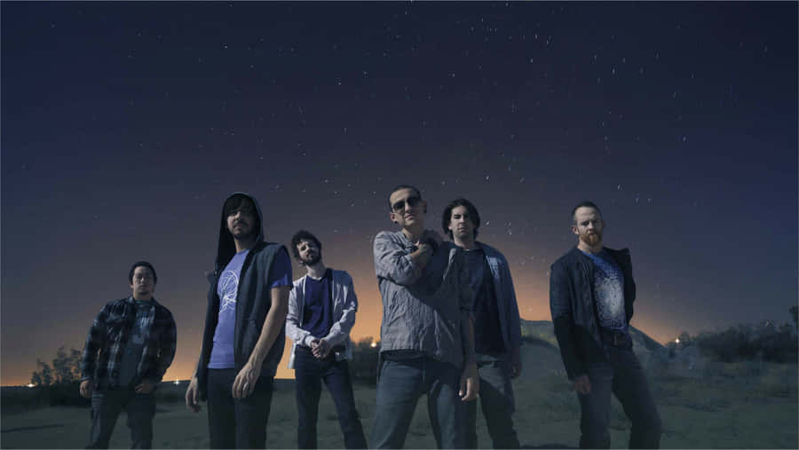 A Group Of Men Standing In A Field With Stars In The Sky Wallpaper