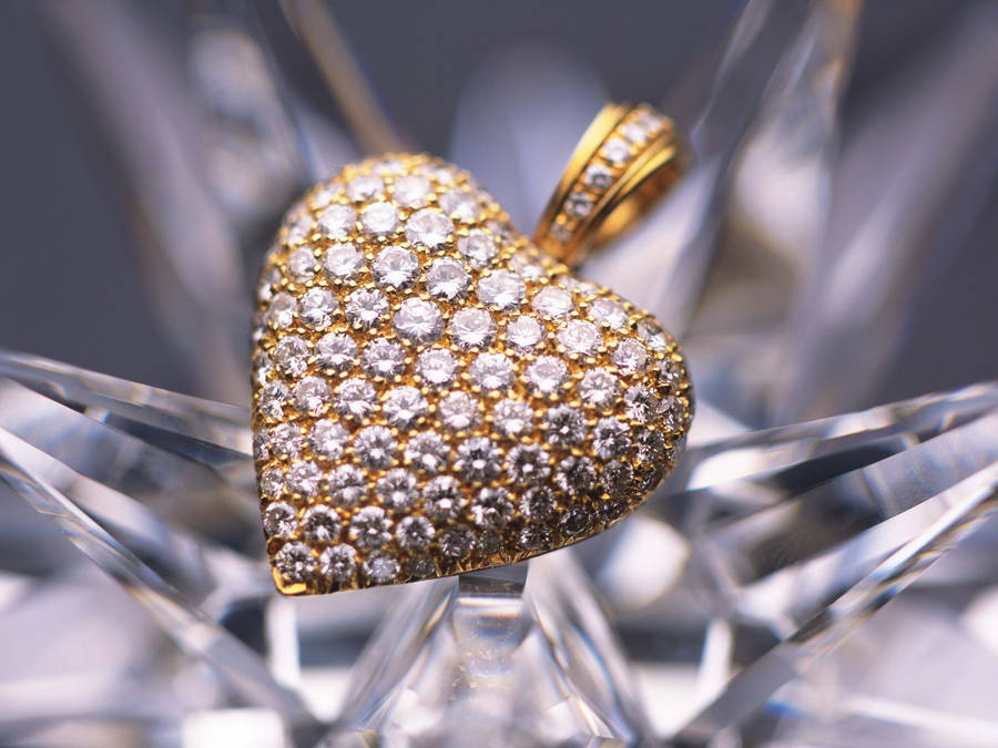 A Heart-shaped Piece Of Gold Jewelry With Emeralds Wallpaper