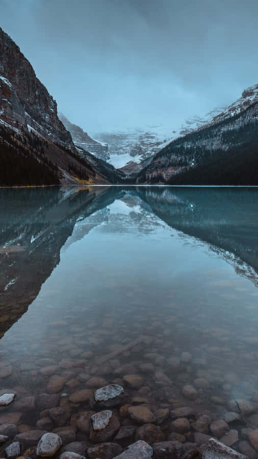 A Lake With Rocks And A Mountain In The Background Wallpaper