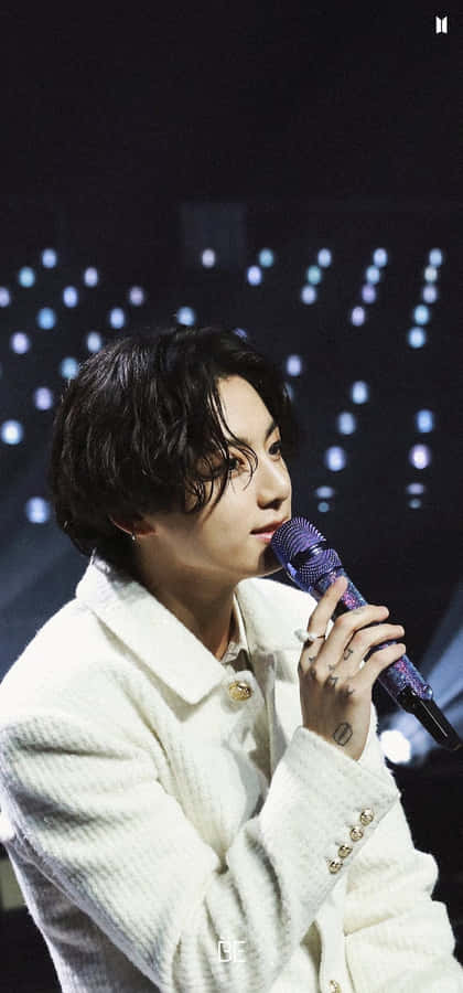 A Man In A White Jacket Is Holding A Microphone Wallpaper