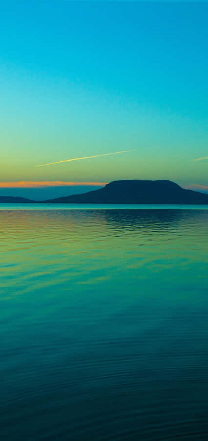 A Man Is Riding A Boat On A Lake At Sunset Wallpaper