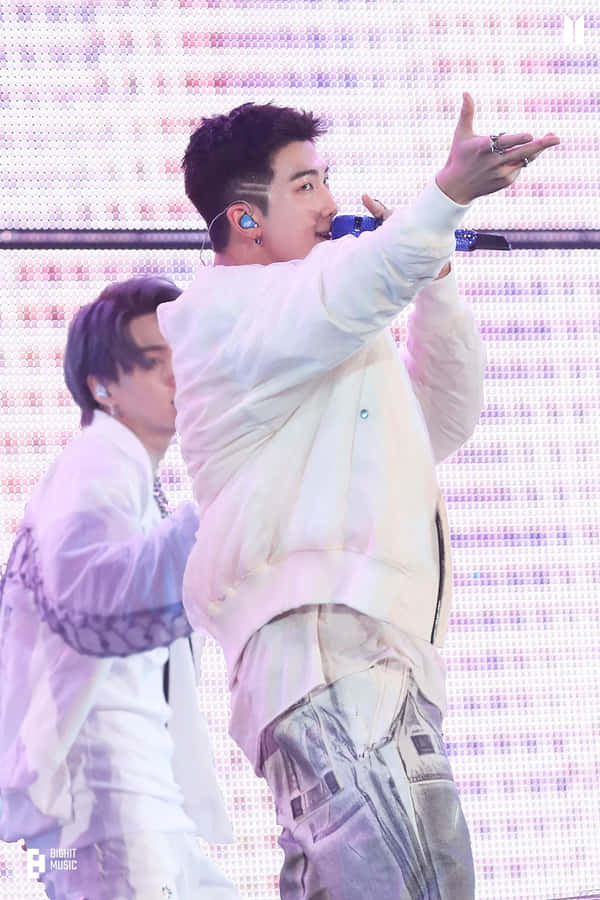 A Man Is Singing Into A Microphone While Another Man Is Standing Wallpaper