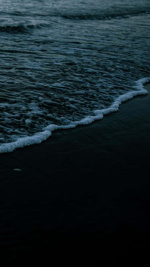 A Man Is Walking On The Beach At Dusk Wallpaper