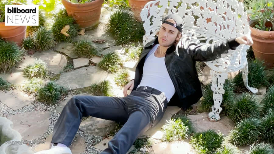 A Man Laying On A White Bench In A Garden Wallpaper