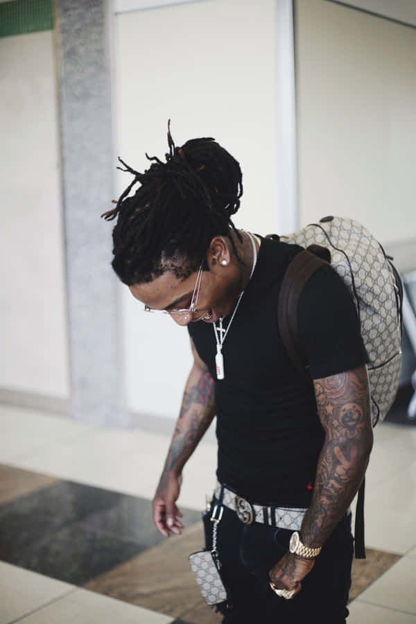 A Man With Dreadlocks Walking Through An Airport Wallpaper