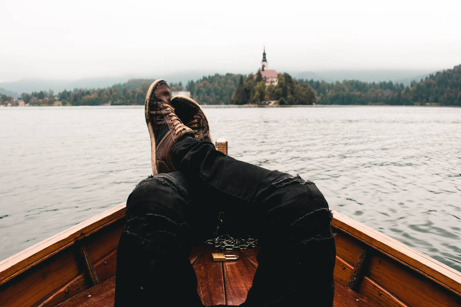 A Person's Feet Are Resting On The Back Of A Boat Wallpaper