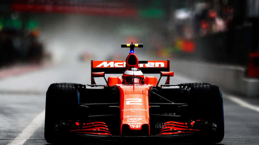 A Red Racing Car Driving Down A Track Wallpaper