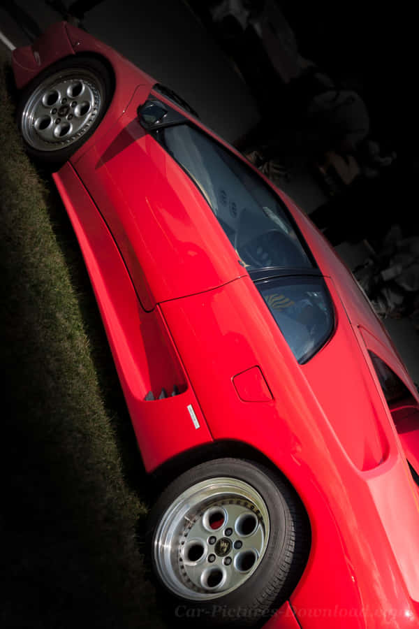 A Red Sports Car Is Parked In The Grass Wallpaper