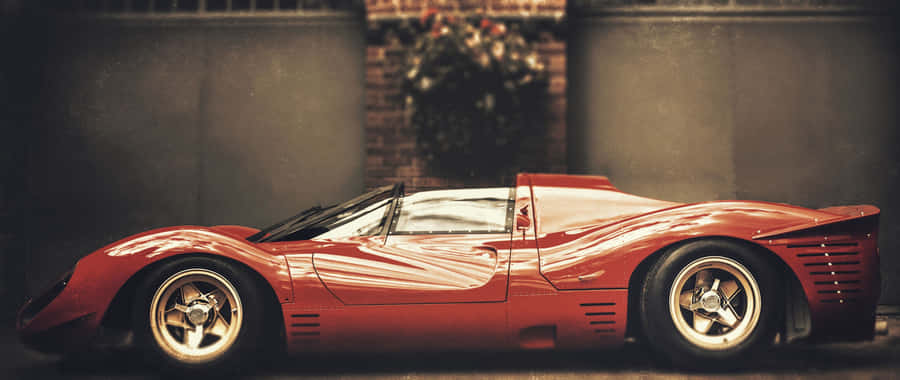 A Red Sports Car Parked In Front Of A Building Wallpaper