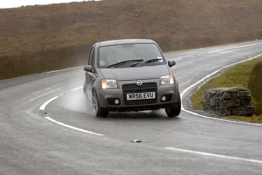 A Sleek Red Fiat Panda Driving Down An Open Road Wallpaper