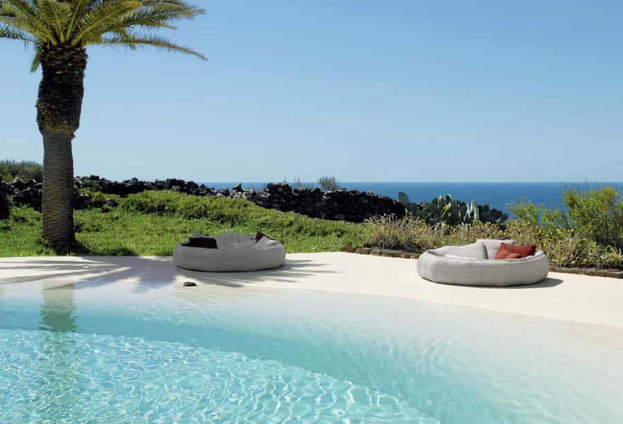 A Stunning Aerial View Of A Beach Swimming Pool By The Ocean Wallpaper