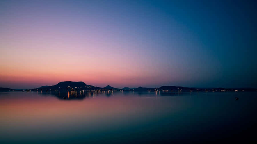 A Sunset Over A Lake With Mountains In The Background Wallpaper