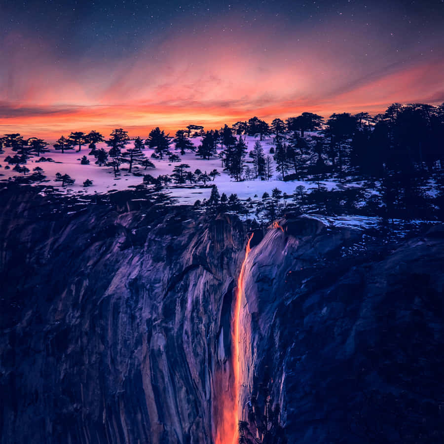 A Waterfall With A Red Glow In The Sky Wallpaper