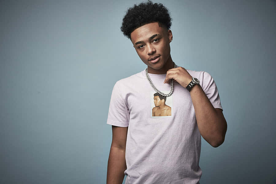 A Young Man Wearing A Pink Shirt And A Necklace Wallpaper