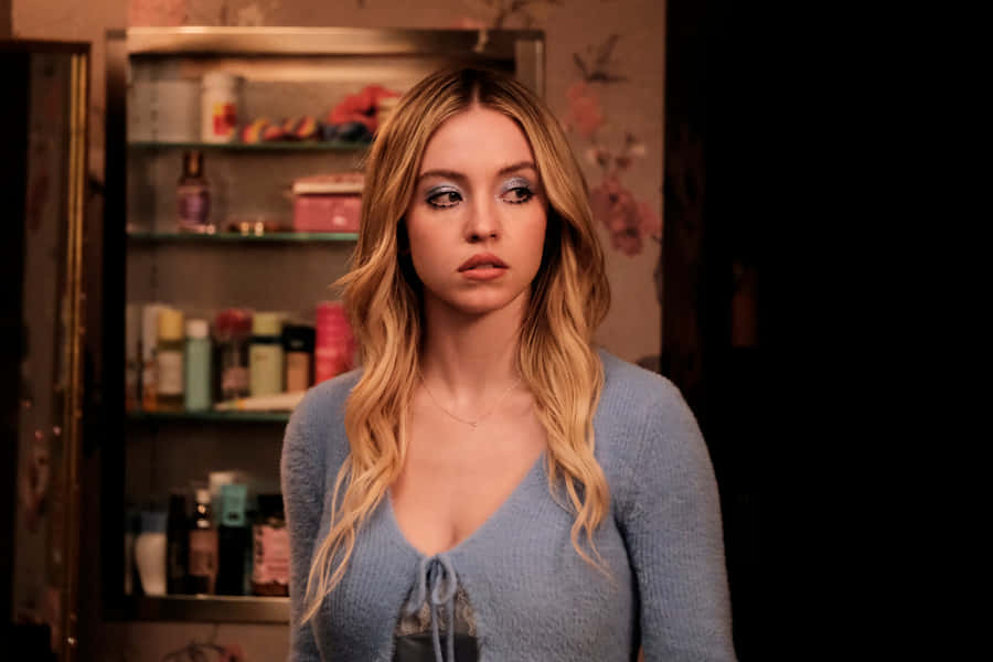 A Young Woman In A Blue Sweater Standing In A Bathroom Wallpaper