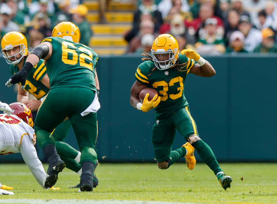 Aaron Jones Of The Green Bay Packers Running The Ball Down The Field. Wallpaper