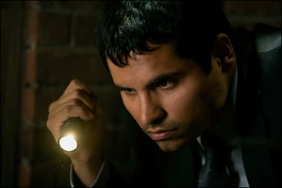 Actor Michael Peña Sporting A Tweed Jacket While Lounging On A Patio Chair