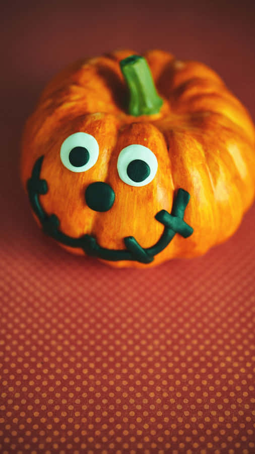 Adorable Smiling Pumpkin With Autumn Leaves Wallpaper