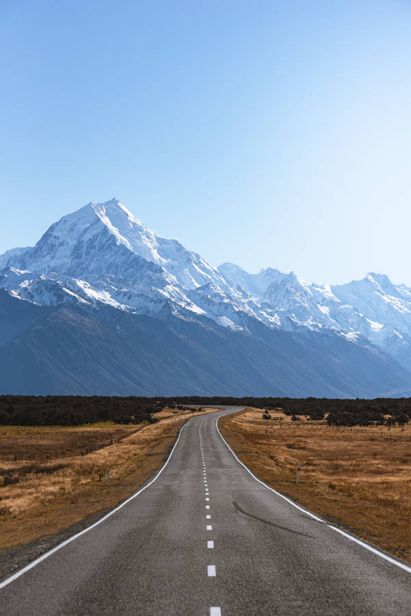 Adventure Is Out There: A View Of The Road Leading To A Mountain Wallpaper