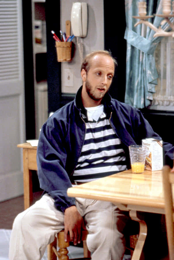 Balding Man Sittingat Kitchen Table Wallpaper